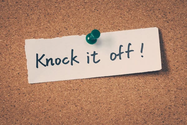 Knock it off - hand written note pushpinned to a corkboard